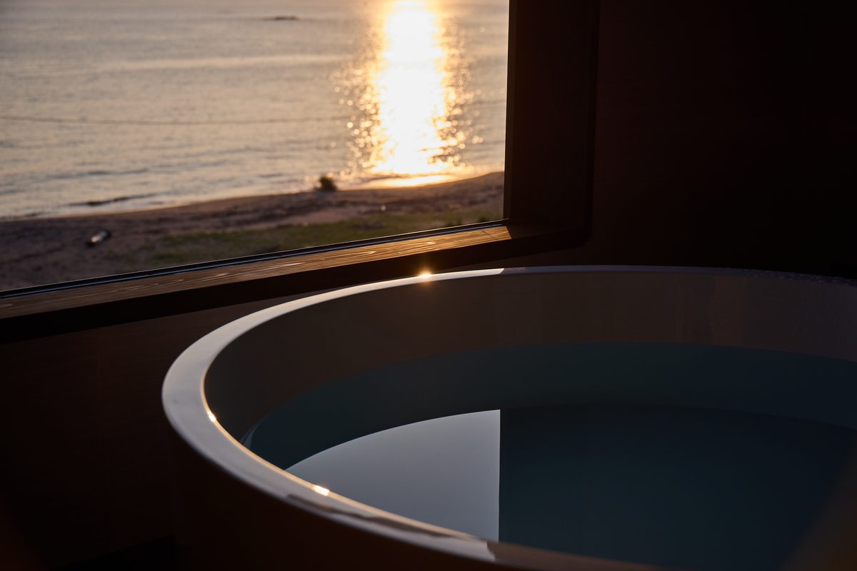 夕陽の海を望む客室の温泉風呂